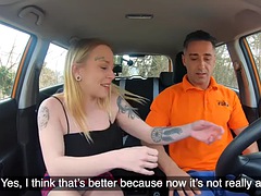 Behind the wheel, pierced and tattooed babe rides a tutor in a car on the street