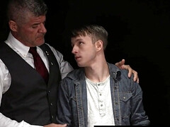 Beefy man in a suit is examining a shy blond fellow